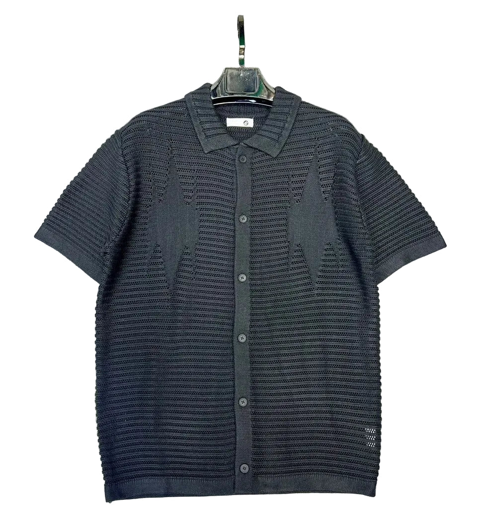 Dark gray knitted shirt on a hanger against a textured gray background