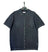 Dark gray knitted shirt on a hanger against a textured gray background